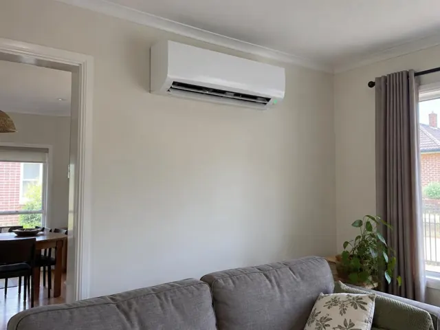 Wall-mounted split system running above a lounge in a cream living room in Enfield